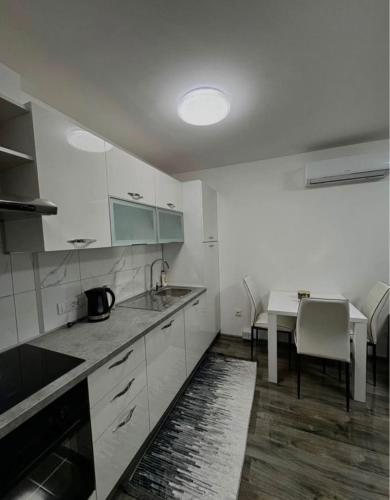 a kitchen with white cabinets and a sink and a table at Jadranka in Vinkovci
