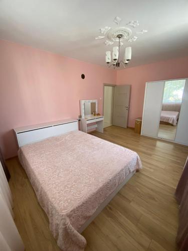 a pink bedroom with a bed and a chandelier at Emis apartment in Targovishte