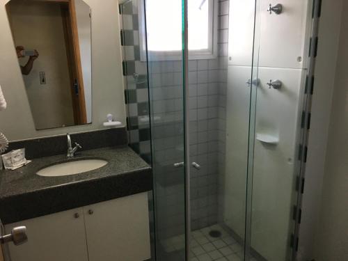 a bathroom with a sink and a glass shower at Hotel Aero Park e Estacionamento in Londrina