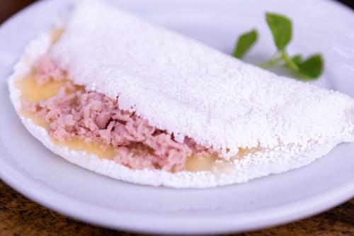 a sandwich with meat and cheese on a white plate at Villa Baepi Pousada Ilhabela in Ilhabela