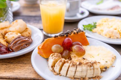 a table with plates of food and a glass of orange juice at Villa Baepi Pousada Ilhabela in Ilhabela