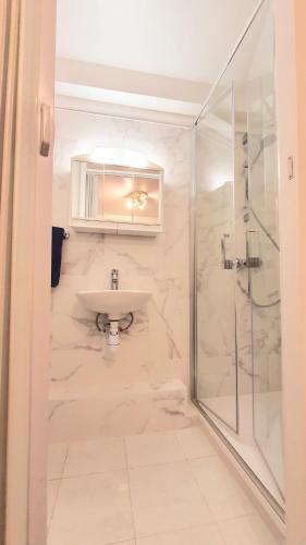 a white bathroom with a sink and a shower at Studio de la maison Lilas in Pila-Canale