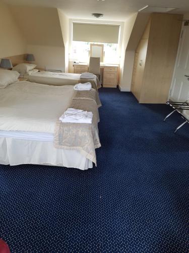 two beds in a room with blue carpet at Aboukir Hotel in Panbride