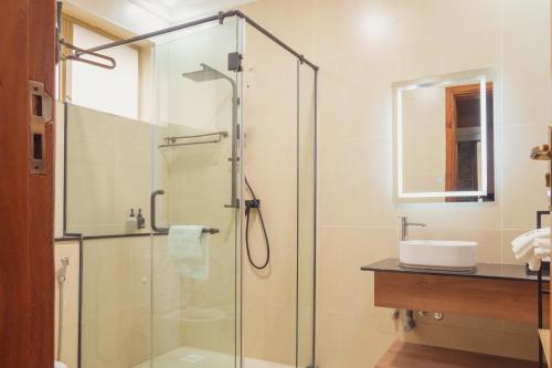 a bathroom with a glass shower and a sink at WOODSY Resort in Nanyuki
