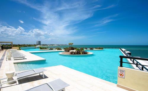 a pool with chairs and the ocean in the background at Ocean's Embrace and unforgetful sunsets in Progreso