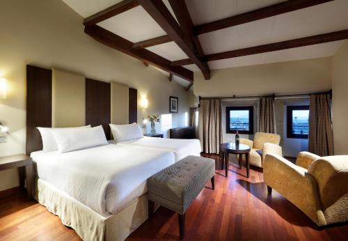 a bedroom with a large white bed and a desk at Eurostars Palacio de Santa Marta in Trujillo