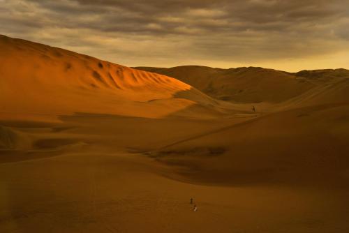 a person walking through a desert with a sand dune at The Upcycled Hostel Huacachina in Ica