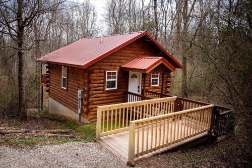 a cabin in the woods with a large wooden deck at Buckeye Bungalow in Logan