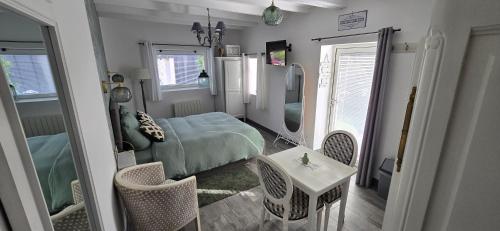 a bedroom with a bed and a table and chairs at Gite "Le Cosy Fleuri" in Champenard