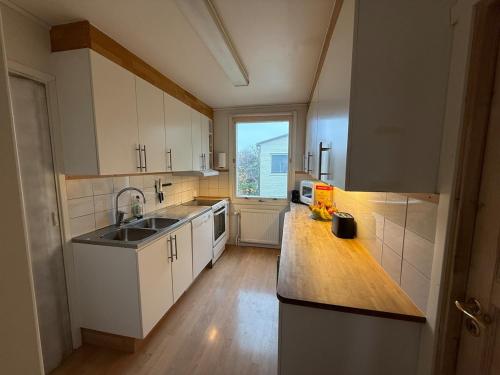 a kitchen with white cabinets and a sink and a window at Spacious flat 15 min to the beach in Falkenberg