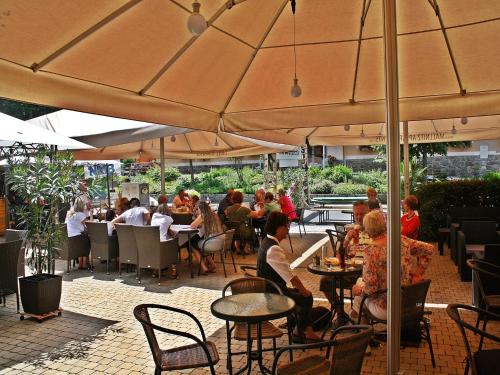 a group of people sitting in a restaurant under umbrellas at Hotel Mallnitz in Mallnitz