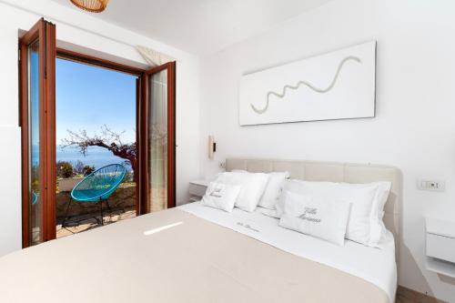 a white bedroom with a bed and a large window at Villa Marianna in Massa Lubrense