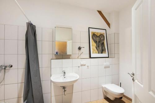 a white bathroom with a sink and a toilet at Seminarhof Mollandur in Bochow