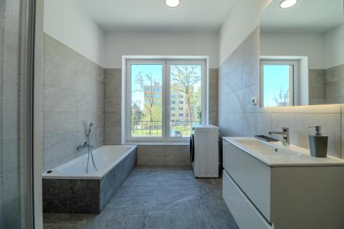 a bathroom with two sinks and a tub and a window at Ubytování U Lesíka in Znojmo