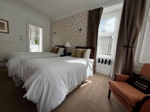 a hotel room with two beds and a chair at Lomond Guest House in Leven