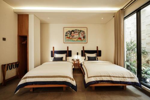 two beds in a room with a window at Dhipa Kinanthi Prawirotaman by Raminten in Timuran