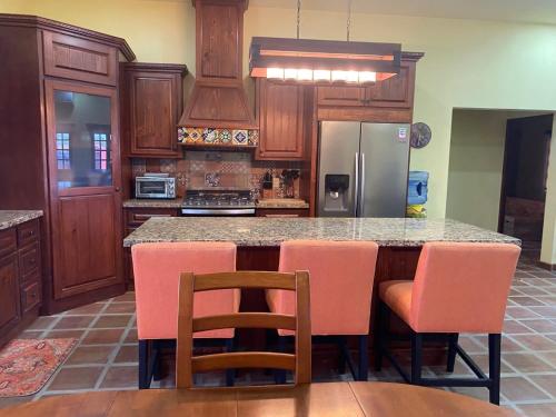 a kitchen with wooden cabinets and a island with pink chairs at Casa Serenidad familiar escapade in San Felipe