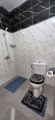 a bathroom with a toilet with a black and white tile wall at DowntownHouse in Midelt in Midelt