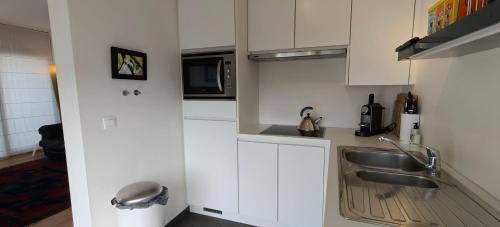 a white kitchen with a sink and a microwave at Zeebrugge Sea View, Family-Friendly & the Beach! in Zeebrugge