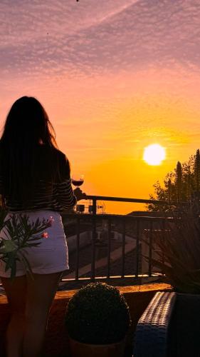 a woman sitting on a balcony watching the sunset at Hôtel Porte de Camargue - Les Quais d'Arles in Arles