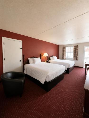 a hotel room with two beds and a chair at Carriage House Inn in Branson