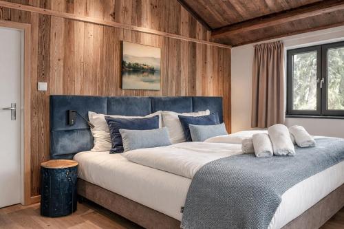 a bedroom with a large bed with a blue headboard at Stylish Loft Apartment with Mountain View near the Lake in Afritz