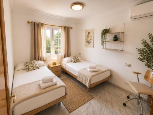 a bedroom with two beds and a window at Villa Savanna Spacious villa with private pool near the beach in Cala en Blanes