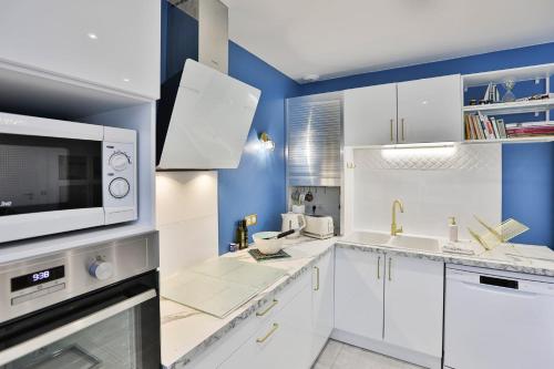 a kitchen with white cabinets and a microwave at Quai Ouest - élégante maison avec piscine in Saint-Vincent-sur-Jard