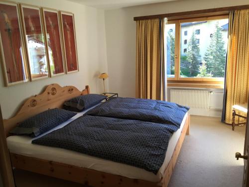 - une chambre avec un lit doté d'une couette bleue et d'une fenêtre dans l'établissement Apartments Chesa Guardaval, à Surlej