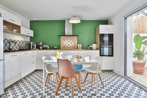 a kitchen with white cabinets and a table with chairs at La Bulle - Maison classée 4 étoiles in Brem-sur-Mer