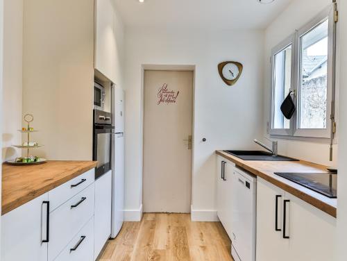 a kitchen with white cabinets and a clock on the wall at Maison des Surfeurs in Les Sables-d'Olonne