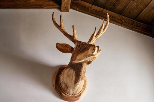 a wooden deer head hanging on a wall at Stylish Loft Apartment with Mountain View near the Lake in Afritz