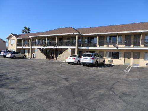 a building with cars parked in a parking lot at Sandpiper Motel in Costa Mesa