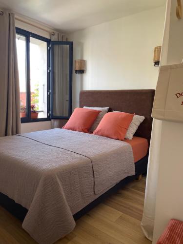 a bedroom with a bed with red pillows and a window at La Clef de la Place in Leucate