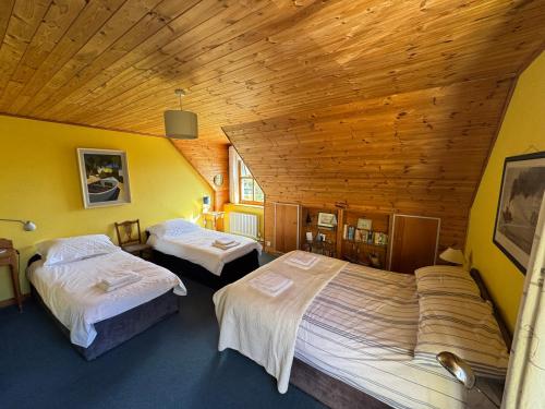 a bedroom with two beds and a wooden ceiling at Kermor B&B in Claddaghduff