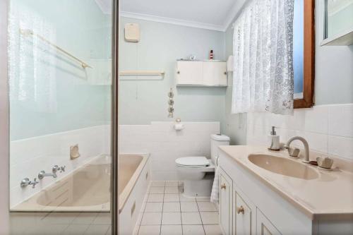 a bathroom with a tub and a toilet and a sink at Spikes Place - Waterfront Serenity for Groups in Hindmarsh Island