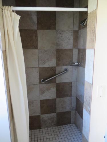 a bathroom with a shower with a shower curtain at Sandpiper Motel in Costa Mesa