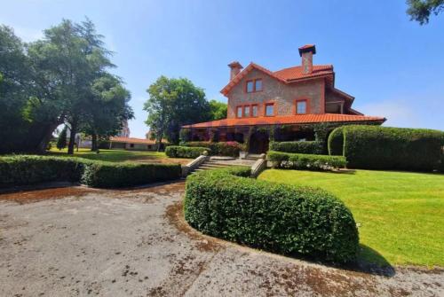 a large house with hedges in front of it at Villa Las tres Mares 6826 in Noja