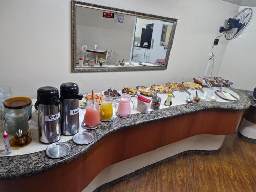 a buffet line with pastries and drinks and a mirror at Hotel Meneghetti Rio Branco in Rio do Sul