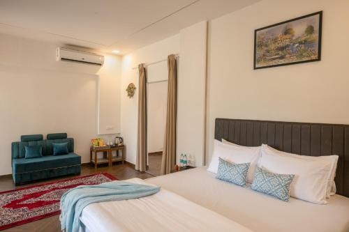 a bedroom with a bed and a blue chair at Amra Woods in Karjat