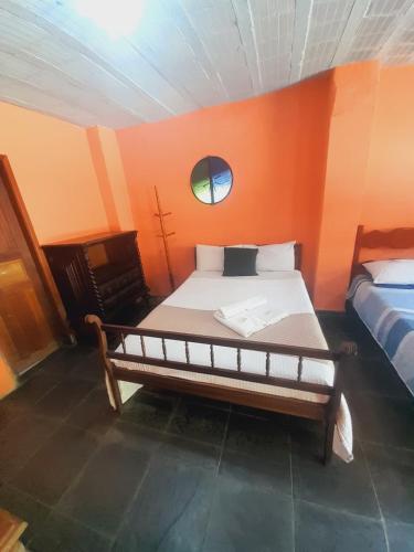 a bedroom with a large bed with an orange wall at Pousada Quinta de Areal in Areal