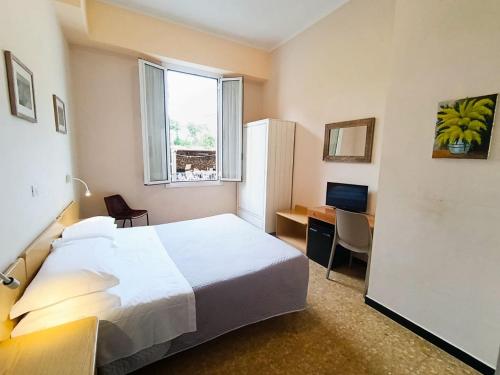 a hotel room with a bed and a desk and a window at Hotel Villa Bianca in Laigueglia