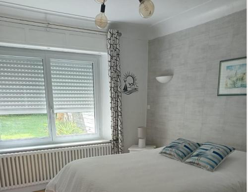 a bedroom with a bed and a window with blinds at apartement avec parking prive in Concarneau