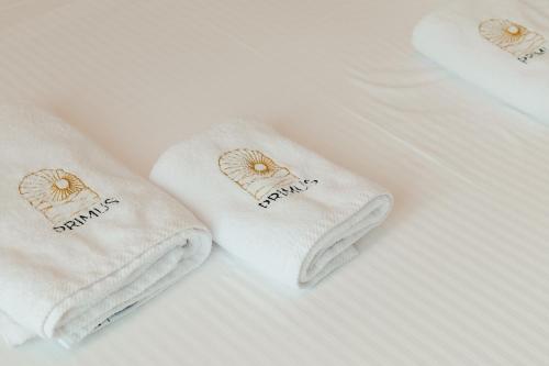 a pair of white towels on a bed at Hotel Primus in Shëngjin