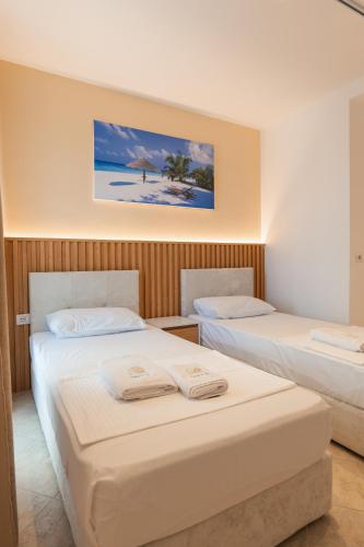 two beds in a hotel room with a picture of a beach at Hotel Primus in Shëngjin