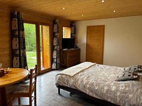 a bedroom with a bed and a table and a television at Le cocon alpin in Passy