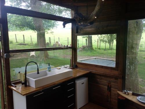 a kitchen with a sink and two windows in a cabin at Le chalet de Montestrucq in Montestrucq