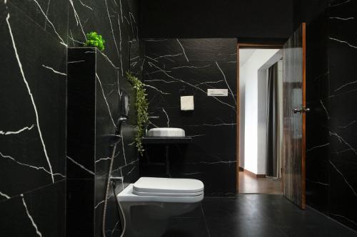 a bathroom with a toilet and a black wall at Amra Woods in Karjat