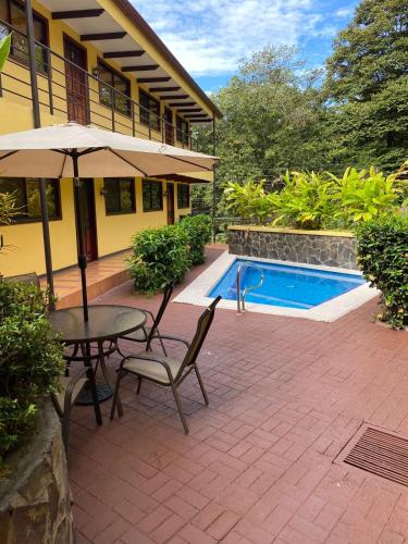 a patio with a table and an umbrella and a pool at Condo Mono Titi in Quepos