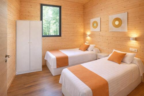a bedroom with two beds and a window at Cabañas Compostela - Cabaña Sarela in Santiago de Compostela
